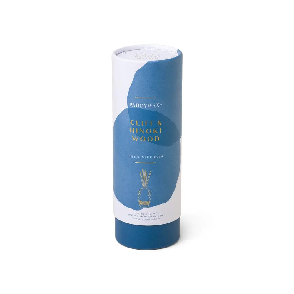 The Santorini 4 fl oz. Diffuser - Cliff & Hinoki Wood comes in a cylindrical blue and white package with gold lettering, inspired by the Aegean Sea.