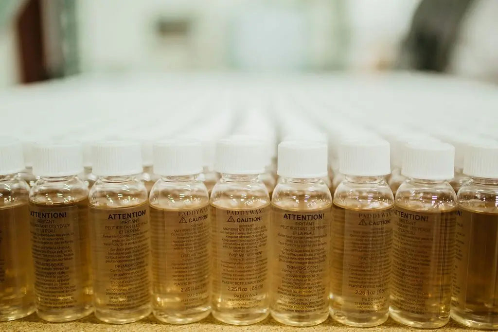 A row of clear plastic bottles filled with liquid, each labeled with cautionary text in both English and French.