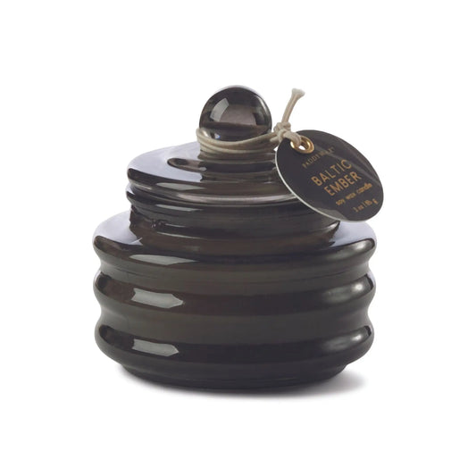 The Baltic Ember - Beam 3 oz Candle features a dark brown ribbed glass jar with a round lid and tag, ideal for adding ambient light and luxury fragrance to any space.