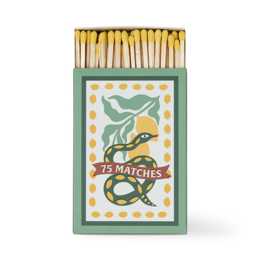 A Dopo "Snake" - 75ct Boxed Matches: Safety matches with yellow tips in a box featuring a green and yellow snake wrapped around a "75 MATCHES" banner, accented by green leaves and yellow dots. The perfect match for your A Dopo candle.