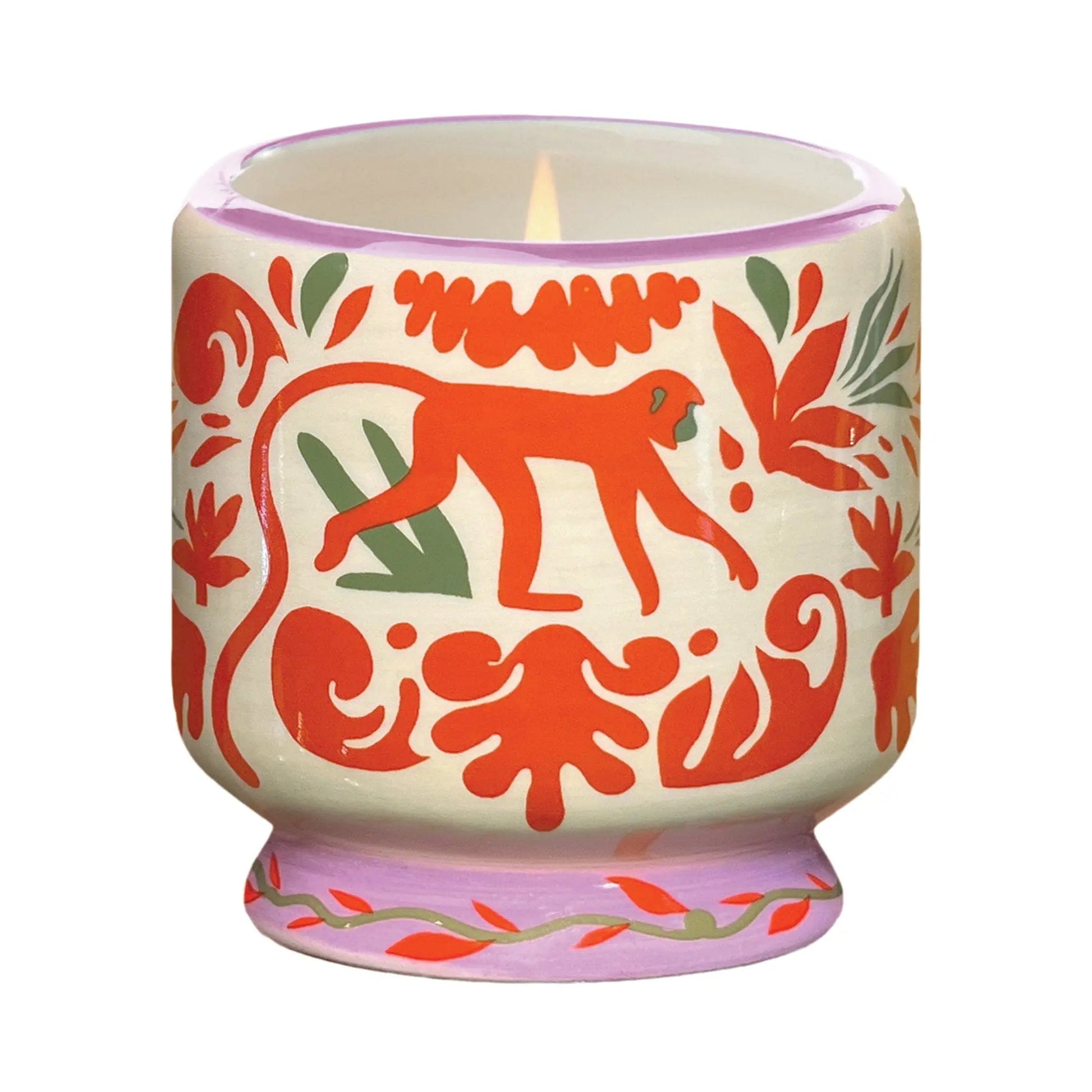 The Coconut & Amber - A Dopo 8 oz Candle comes in a lit ceramic holder with red and green animal and leaf patterns, featuring a central red monkey—perfect for fans of bold fragrance candles.