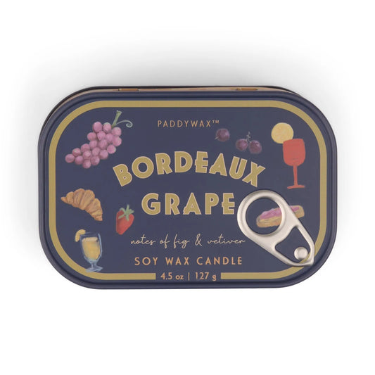 The Bordeaux Grape - Bistro 4.5 oz Tin Candle features colorful illustrations of grapes, figs, a croissant, a drink, and a wine glass on a dark background. A pull-tab lid adds charm to this Bistro-scented tin candle.