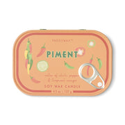 The Piment - Bistro 4.5 oz Tin Candle features a vibrant orange tin adorned with whimsical illustrations of chili peppers and mango slices. The playful label showcases notes of chili pepper and tropical mango, beautifully capturing the signature Piment fragrance in this fruit-and-spice-inspired soy wax candle. Weighing 4.5 oz / 127 g, it comes complete with a convenient pull-tab lid for easy use.