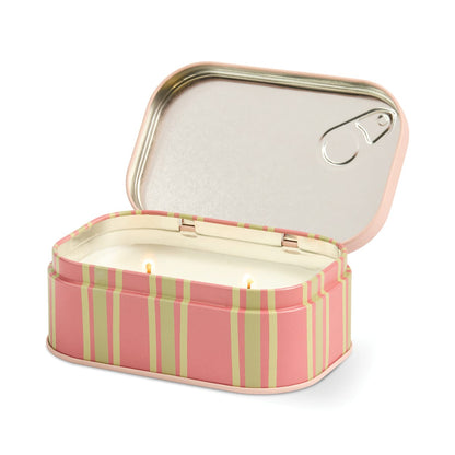 A pink and green striped metal tin, shaped like a sardine can with the lid partially opened, reveals a Bistro 4.5 oz Tin Candle (Martini) inside featuring two unlit wicks.