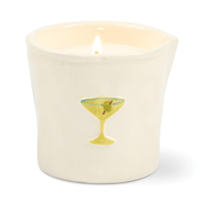 A lit Martini - Bistro 8 oz Candle in a white ceramic holder, hand-painted with a yellow cocktail glass featuring two olives on the front.