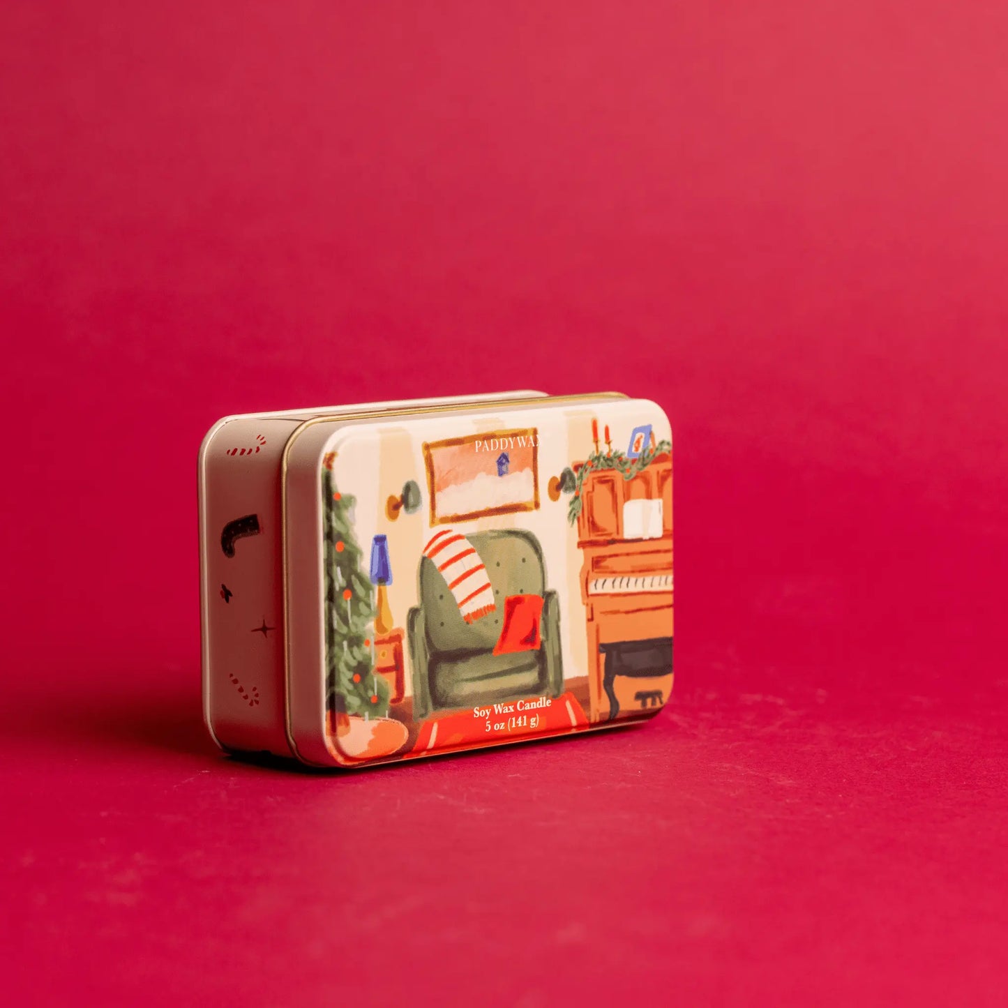 On a red background, 5 oz holiday tin with custom artwork; lid shows family room with piano and decorated tree 