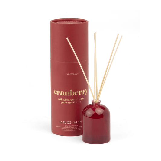 A Cranberry - 1.5 oz Diffuser features a red cylindrical container paired with a matching diffuser bottle and wooden reeds, making it a stylish, giftable home fragrance set.