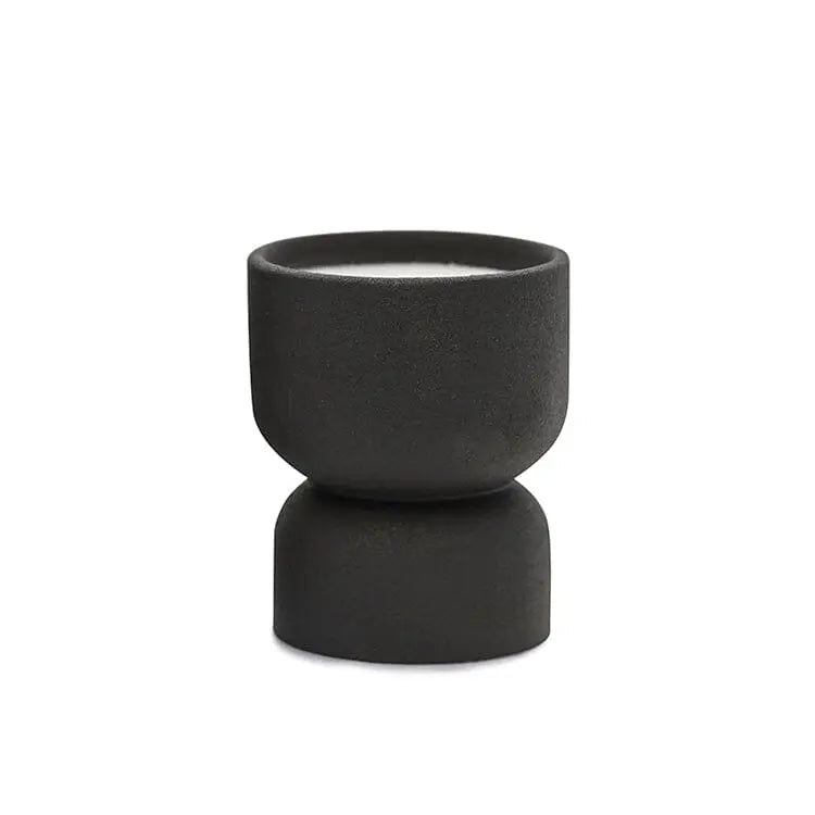 The Palo Santo Suede - Form 6 oz Candle features a small, black matte ceramic holder with a modern hourglass design. It includes a white candle and is ideal for desert-inspired decor—reuse it as a planter. Shown on a plain white background.