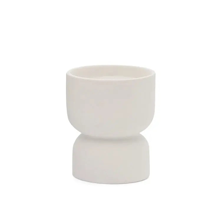 The Tobacco Flower - Form 6 oz Candle features a small, white ceramic hourglass-shaped cup that brings subtle elegance to any setting—ideal for desert-inspired decor with its refined design and clean white finish.