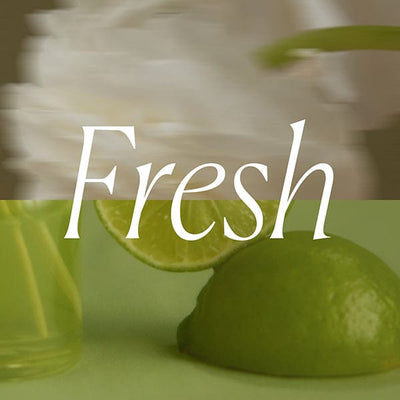 A sliced lime on a green surface with a blurred white flower in the background and the word Fresh overlaid in white text.