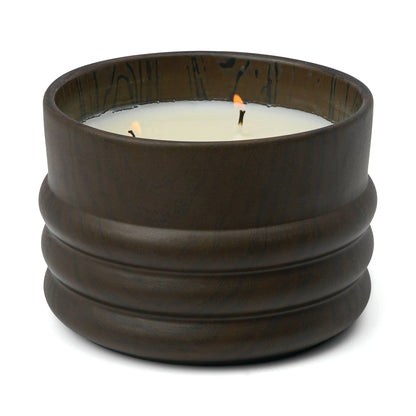The Tobacco & Patchouli - Grain 12 oz Candle features a brown ribbed ceramic container with a lit white three-wick candle, filling the air with a rich tobacco patchouli scent.