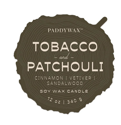 The Tobacco & Patchouli - Grain 12 oz Candle features a brown wood-textured label and a rich blend of cinnamon, vetiver, sandalwood, and patchouli; perfect for fans of woodsy-scented soy candles by Paddywax.