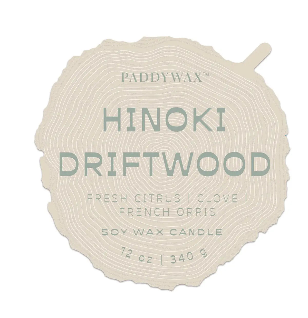 A wood slice-shaped label reads: Paddywax Hinoki Driftwood - Grain 12 oz Candle, Fresh Citrus, Clove, French Orris, Soy Wax, 340g.