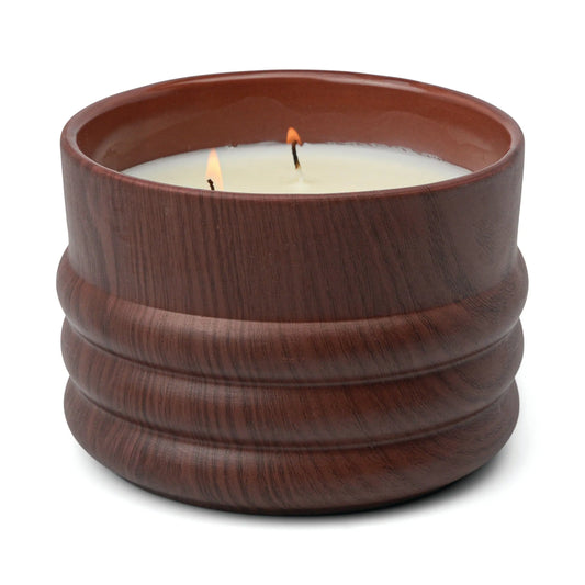 The Bergamot & Mahogany - Grain 12 oz Candle has two wicks and comes in a brown ribbed ceramic jar, part of the Woodgrain Candle Collection. It features notes of bergamot and mahogany.