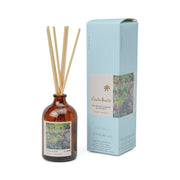 The Claude Monet Secret Garden Impressionist Diffuser (2.7 fl oz) features a brown glass reed diffuser with wooden sticks beside a blue box adorned with floral art—an ideal gift for fans of Impressionist candles and artistic home décor.