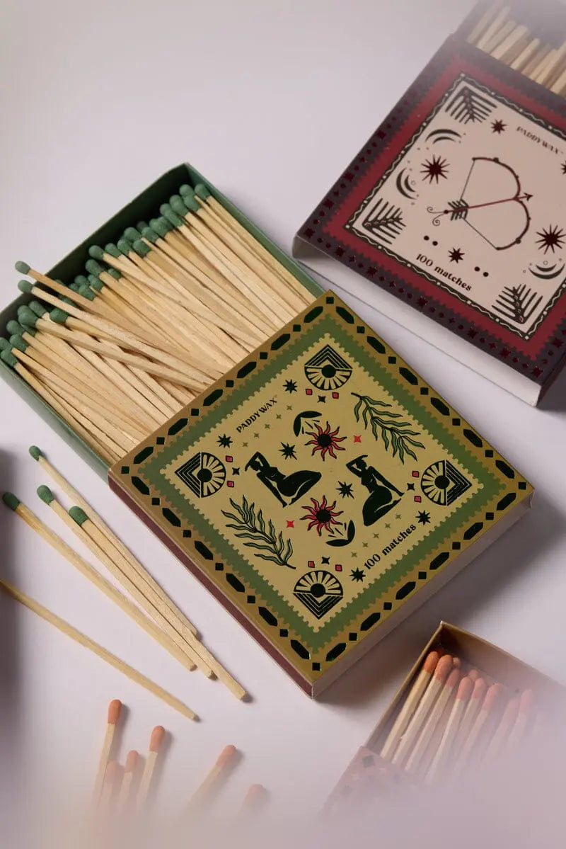 Three open Femme - Green Matches boxes with decorative lids display jumbo green-tipped matches, arranged on a white surface—the perfect candle accessory.