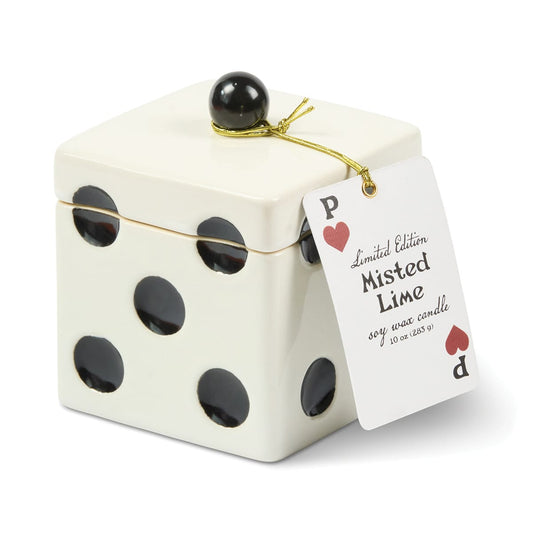 A cream-colored, cube-shaped Misted Lime - Lucky Dice 10 oz Candle jar decorated with black dots, topped with a black sphere handle and a playing card tag.