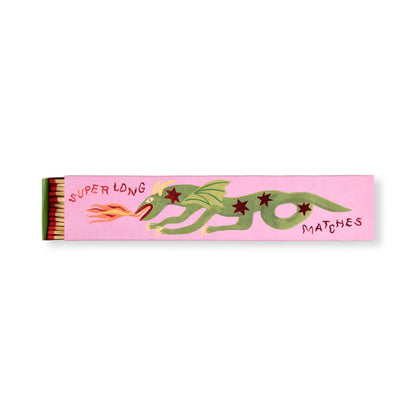 A pink box labeled Dragon - Extra Long Boxed Matches showcases a green fire-breathing dragon, making it ideal dragon decor. When opened, the box reveals extra long matches inside.