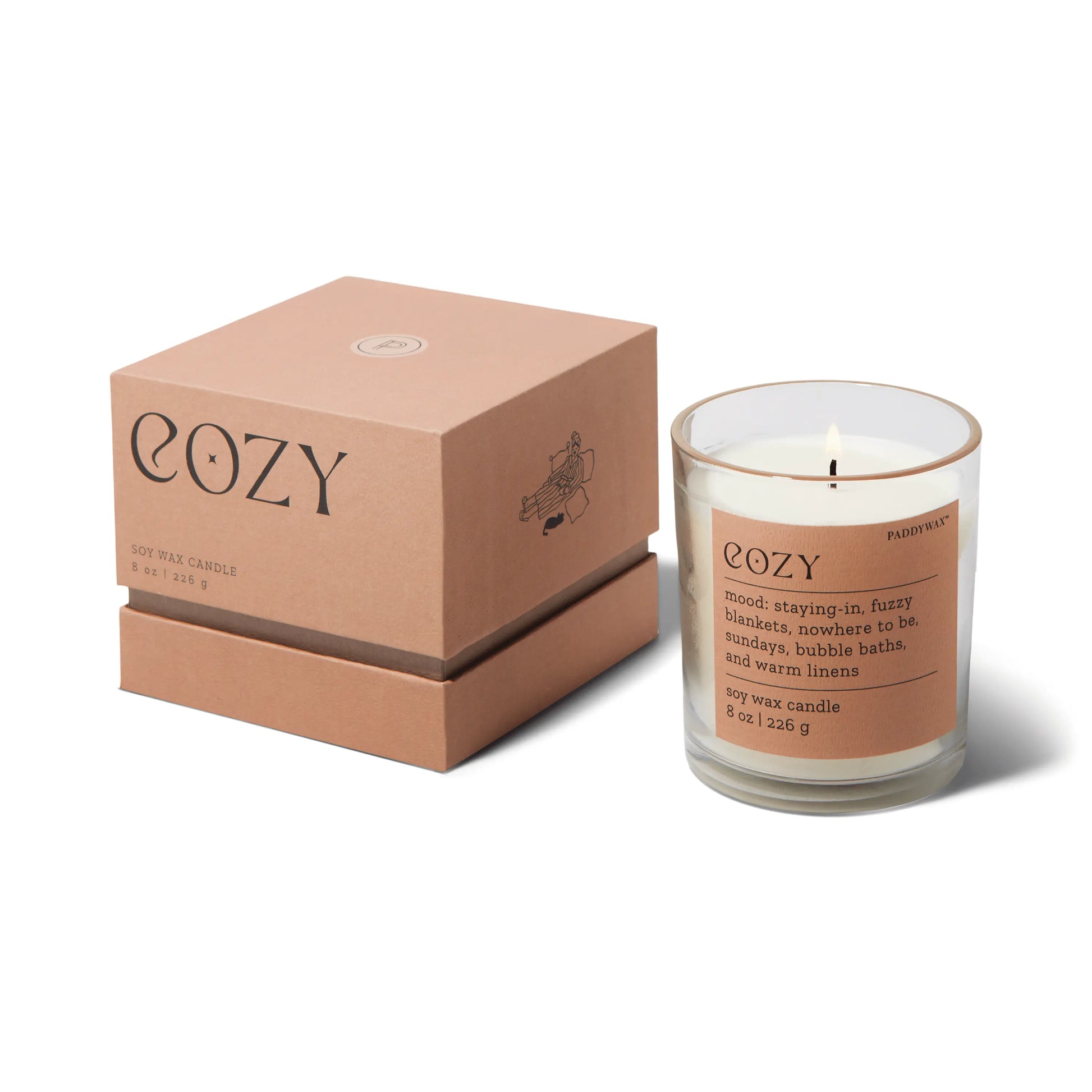 The Mood Collection 8oz - Cashmere + French Orris "Cozy" candle comes in a glass jar with a brown label, paired with a matching box. Its scent creates comfort and relaxation, making it perfect for a soothing, cozy atmosphere.