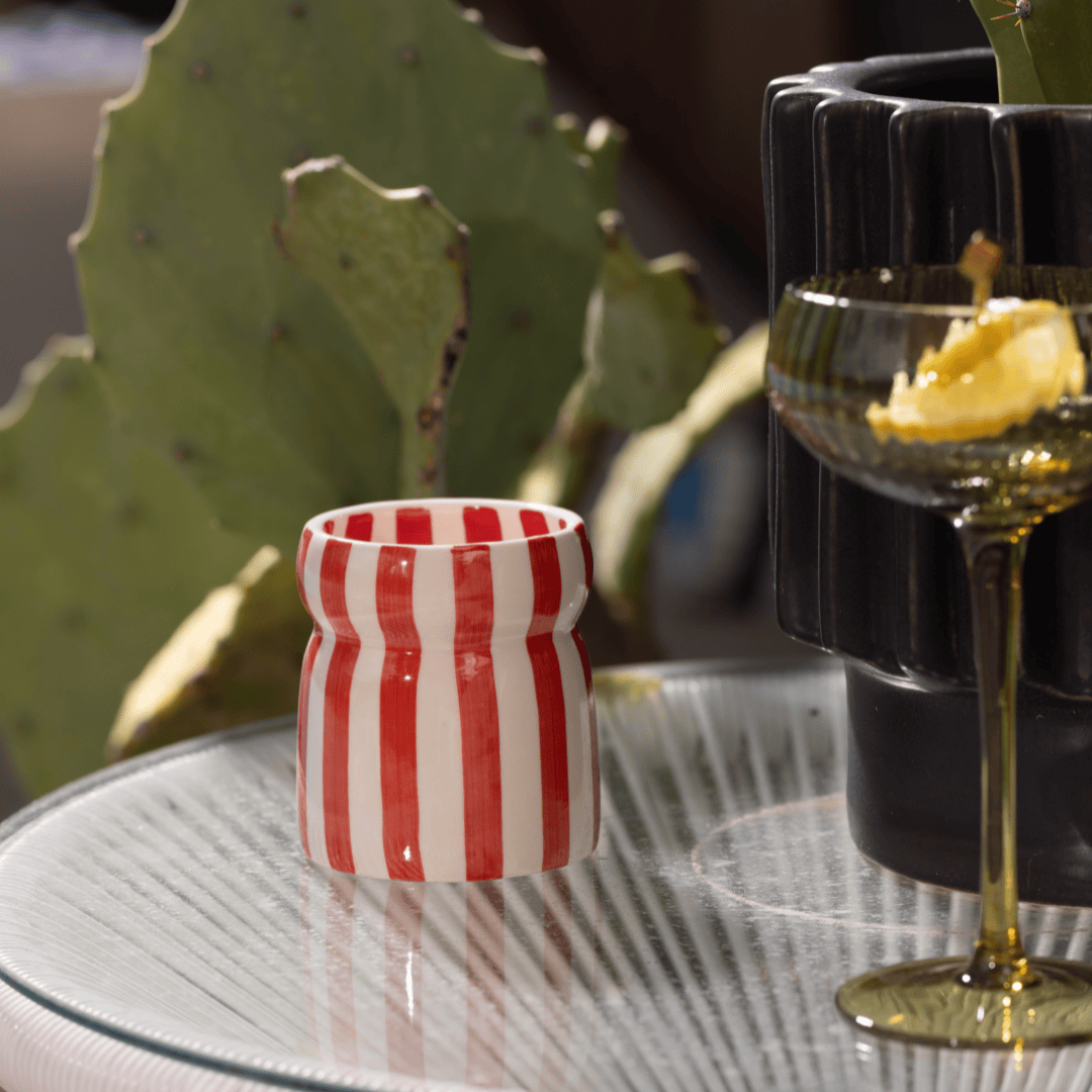 The Hibiscus Bay - Cabana 6.5 oz Candle sits on a table, adding charm to the setting.