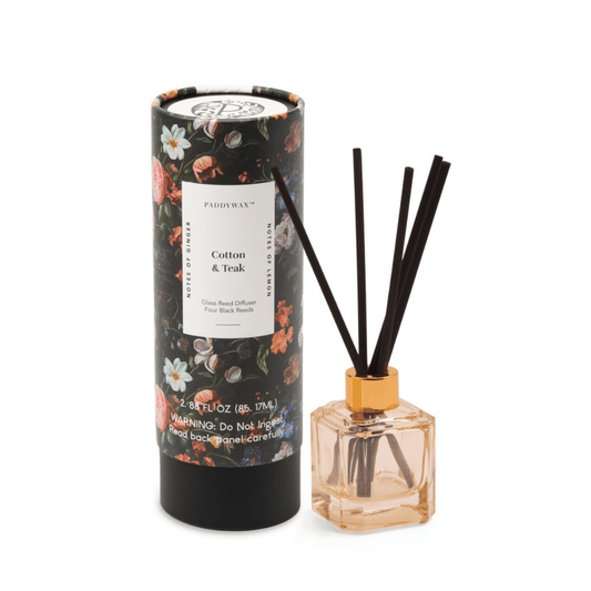 The Cotton + Teak - Botanica Diffuser 2.88 oz comes in a floral box with a glass bottle, fragrance oil, and black reeds—a modern touch to elevate any space.