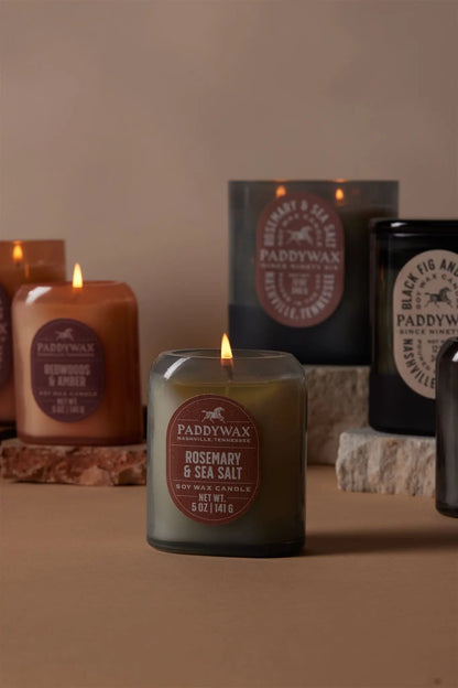 The Vista 5 oz Candle in Rosemary & Sea Salt by Paddywax fills the modern home with luxurious fragrance. Its elegant design and color stand out beautifully on a neutral surface accented with stone decor.