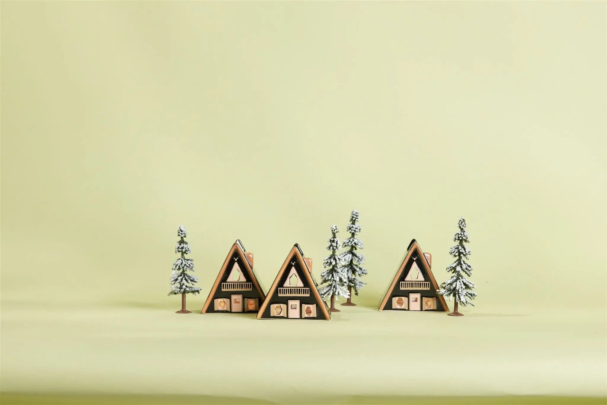 No. 01 The Nordic Cabin - Incense & Tea Light Holder is shown among pine trees and a snowy A-frame cabin village scene on a light yellow background, inspired by Scandinavian décor.