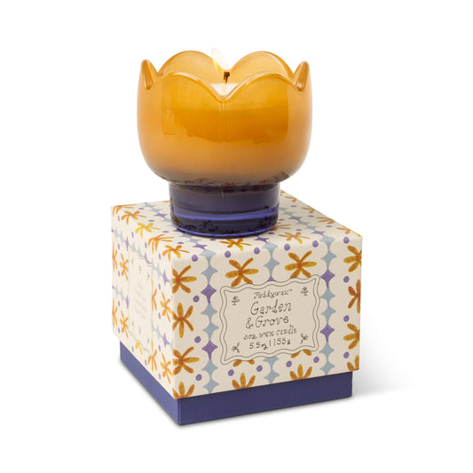 The Garden & Grove - Tulip 5.5 oz Candle by Paddywax is a brown and purple, scalloped candle on a floral box. Lit, it features orange and purple flowers for rustic botanical charm.