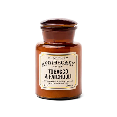 The Tobacco + Patchouli - Apothecary 8 oz Candle is a brown glass jar soy wax candle featuring a vintage-inspired scent, adding a touch of luxury fragrance to your home.