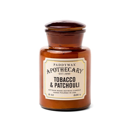 The Tobacco + Patchouli - Apothecary 8 oz Candle is a brown glass jar soy wax candle featuring a vintage-inspired scent, adding a touch of luxury fragrance to your home.