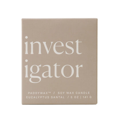 A beige ombre glass box displays "investigator" in bold white letters. Below: Enneagram #5 Investigator 5 oz Candle – Eucalyptus Santal, a Paddywax soy wax candle and thoughtful gift.