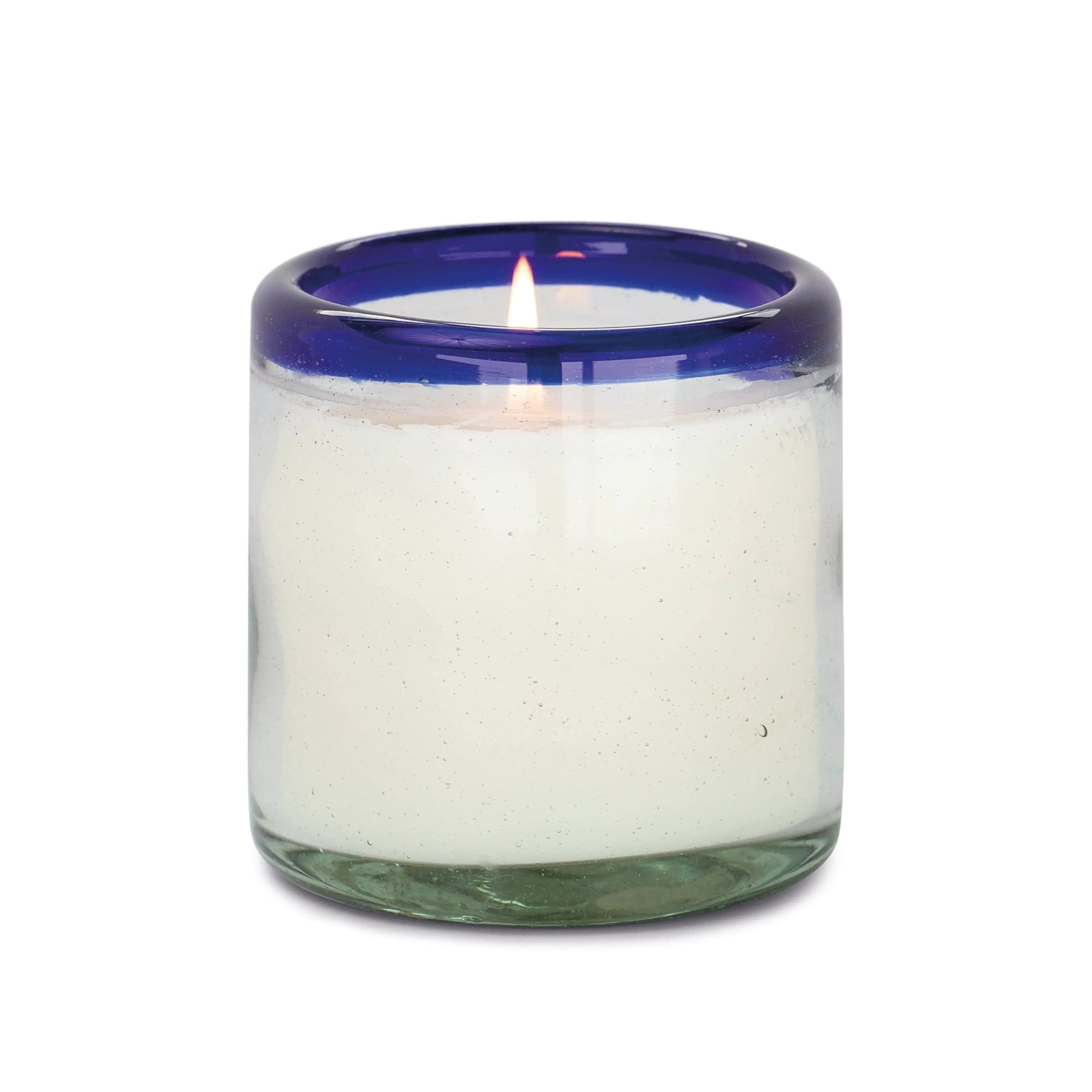 The Salted Blue Agave - La Playa 9 oz Candle is a lit white candle in a clear, hand-blown bubble glass holder with a thick blue rim.