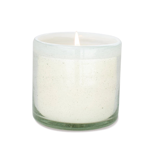The Amber + Coconut - La Playa 9 oz Candle glows in a clear, hand-blown bubble glass container against a plain white background.