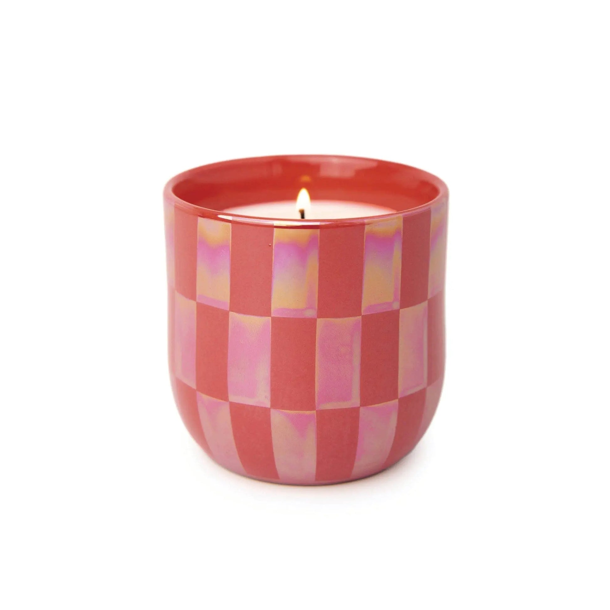 A lit Cactus Flower - Lustre Candle 10 oz glows in a pink, checkered ceramic holder against a white background.