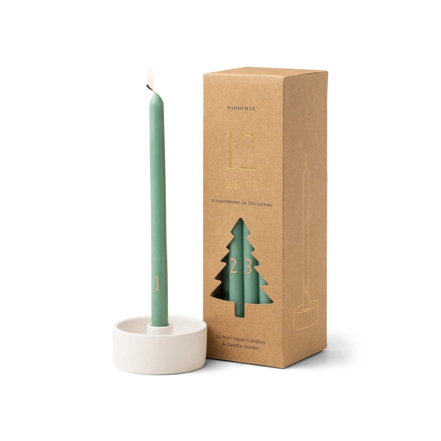 A green taper candle with the number 1 in a white holder sits beside a brown box with a tree cutout and the numbers 1 and 23, labeled "12 Days: A Countdown to Christmas." The Cypress + Fir Taper 12 Days of Christmas Countdown Candle Set is a festive choice for holiday gifting or celebrating with a classic 12 Days of Christmas candle tradition.