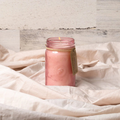 The Salted Grapefruit - Relish 9.5 oz Candle is housed in a pink upcycled glass jar with a label, set on light fabric against a neutral backdrop—ideal for adding a fragrant, decorative touch to your home.