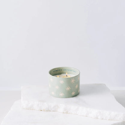 Green ceramic candle with sparkles and white soy wax center with three wicks burning 