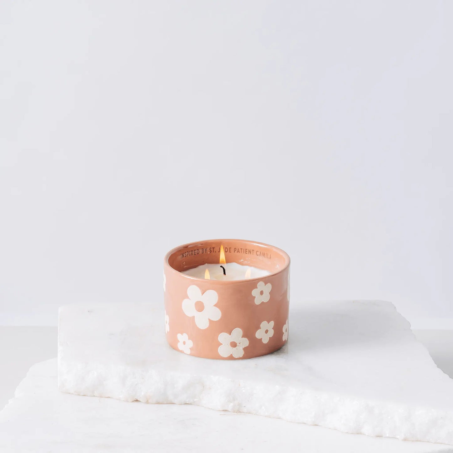 Pink ceramic candle with flowers and white soy wax center with three wicks burning 