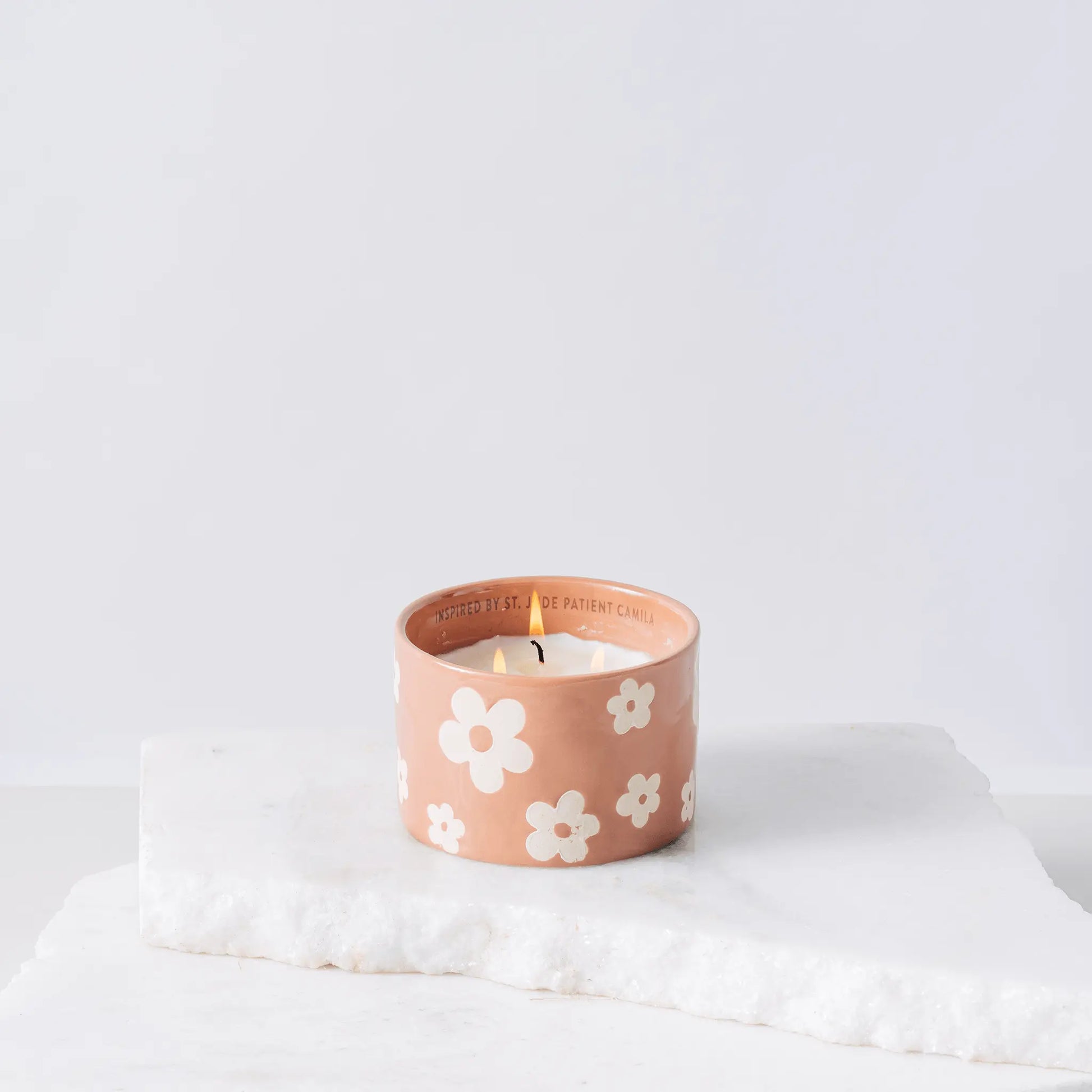 Pink ceramic candle with flowers and white soy wax center with three wicks burning 